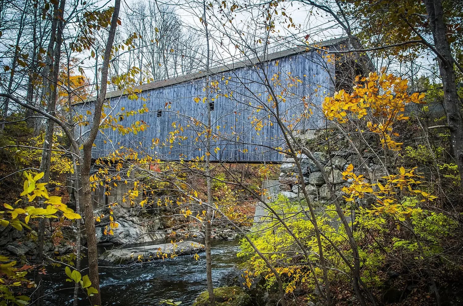 Bull's Bridge, a covered bridge over the Housatonic River in Kent, Connecticut, surrounded by autumn foliage